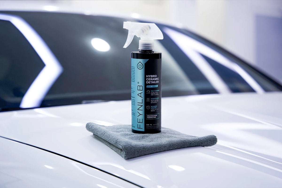 Butelka Feynlab Hybrid Ceramic Detailer i złożona mikrofibra stojące na masce białego samochodu