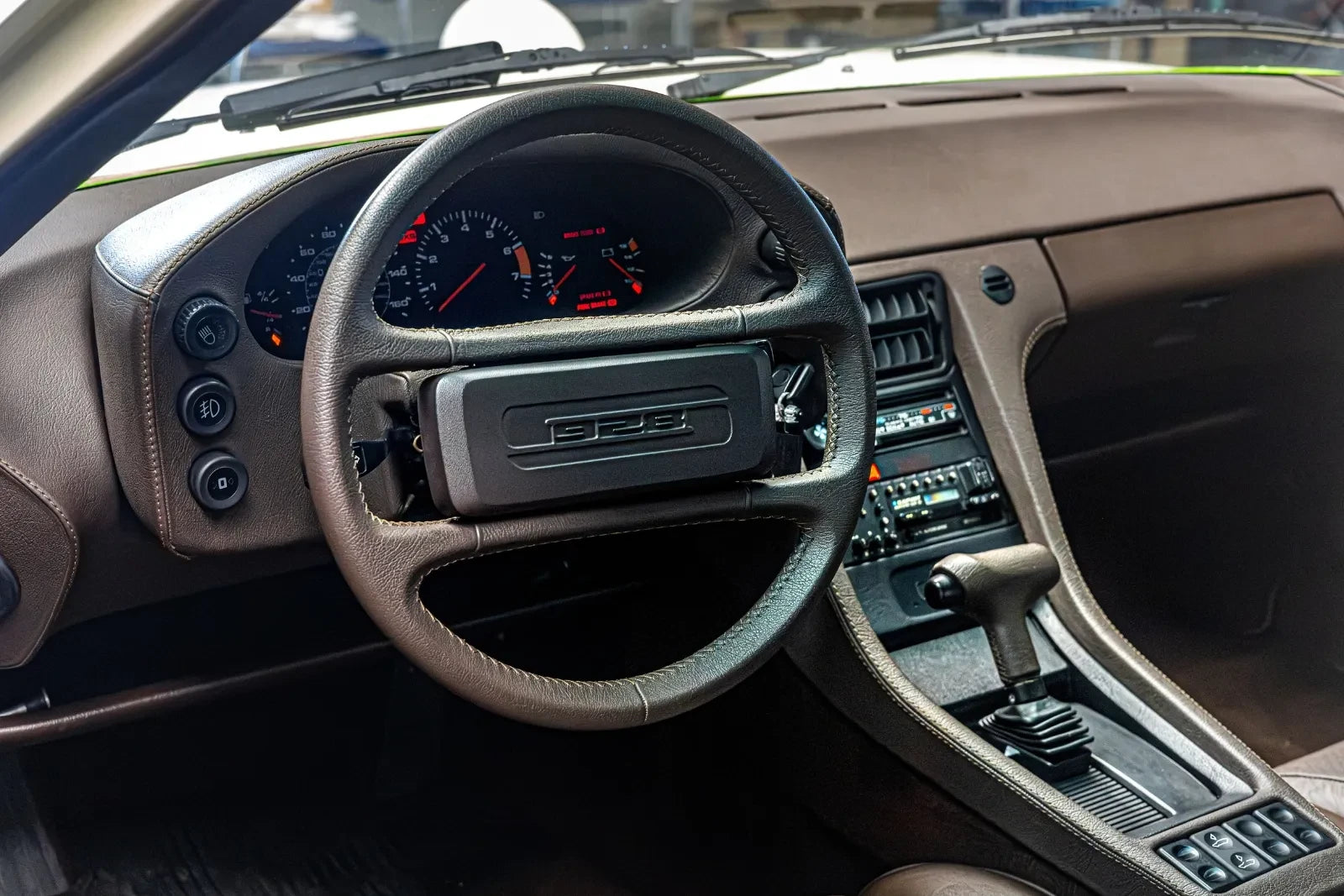 Wnętrze klasycznego Porsche 928: brązowa skóra deski rozdzielczej, skórzana kierownica i konsola środkowa